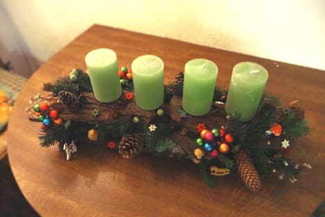Selbstgemachtes längliches Adventsgesteck mit grünen Kerzen und Baumrinde